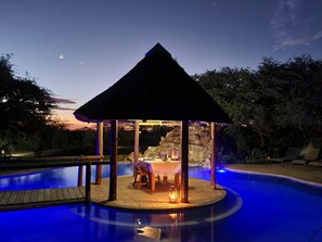 A gazebo with a table and chairs, surrounded by a swimming pool. - Mattanu Private Game Reserve (Dikgatlong)