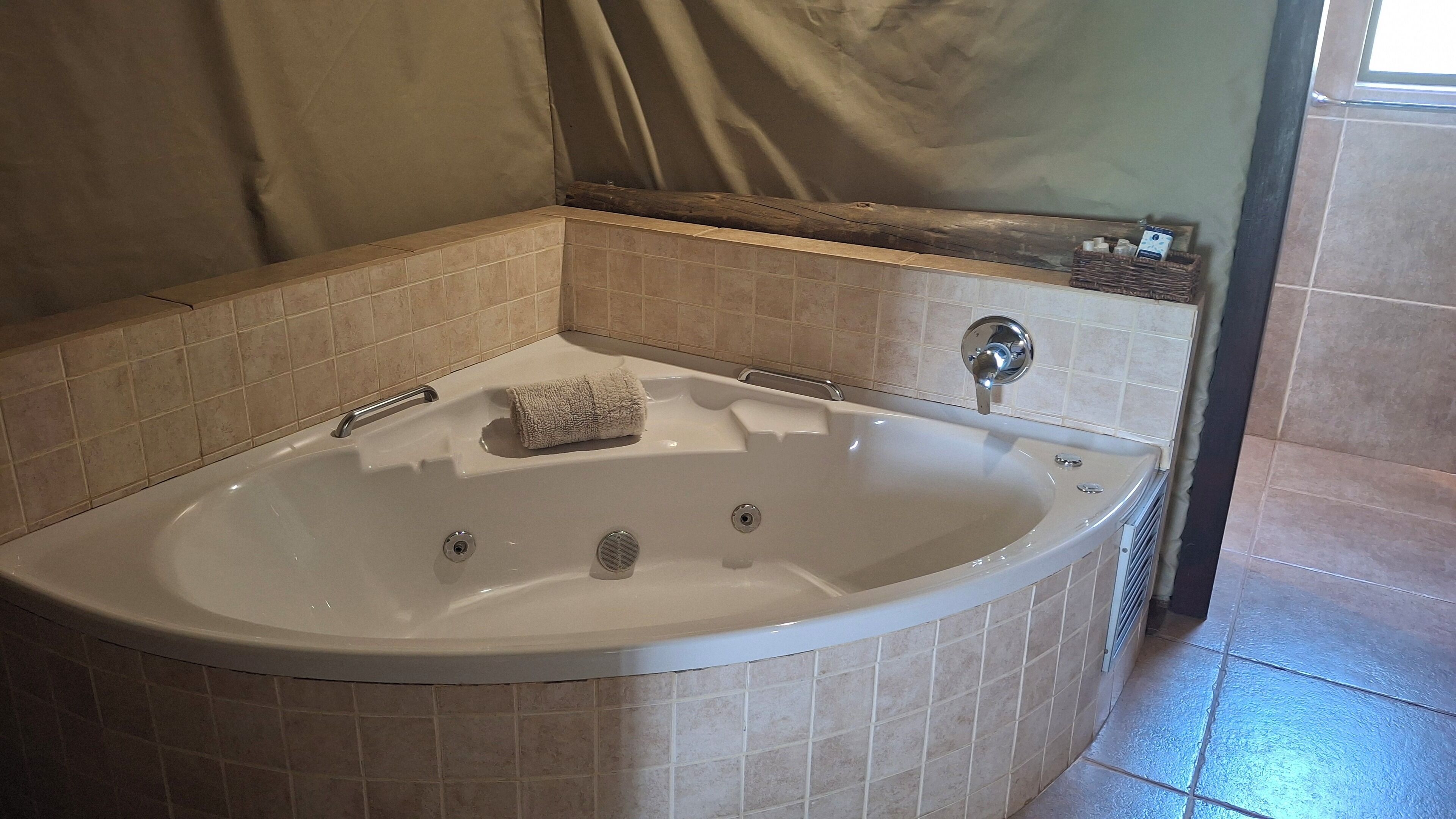 Un baño con una bañera independiente, una toalla y un espejo encima.