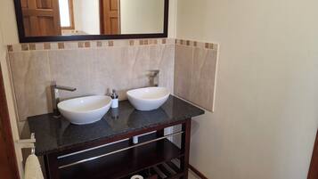 A bathroom with two white vessel sinks, a dark granite countertop, and a mirror above the sink.