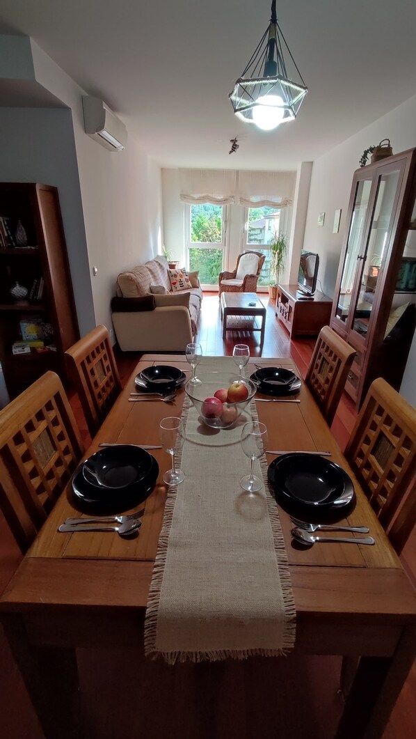 A dining area with a wooden table set for two, a bowl of fruit, and a hanging light fixture. - Charming, with views, comfortable and centrally located. Close to the river and the National Park. (Boltaña)