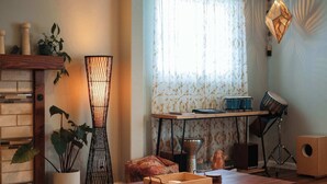 A cozy living room with a fireplace, a tall floor lamp, a wooden table, and a window with patterned curtains. - Tahoe Trail Retreat Steps From the TRT (Stateline)