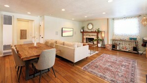 A living room with a wooden dining table, a sofa, a fireplace, and a patterned rug. - Tahoe Trail Retreat Steps From the TRT (Stateline)