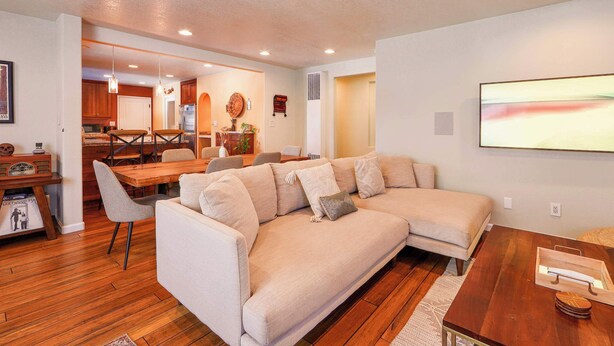 A modern living room with a beige sectional sofa, wooden dining table, and a wooden coffee table. - Tahoe Trail Retreat Steps From the TRT (Stateline)
