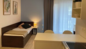 Une chambre à coucher avec un lit, une table de chevet, une lampe et un bureau avec une chaise. Deux tableaux encadrés sont accrochés au mur.