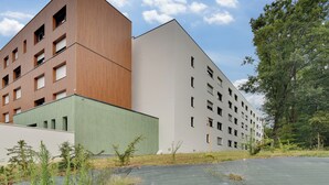 Un bâtiment moderne aux façades composées d’un mélange de bois et de blanc, doté de nombreuses fenêtres et d’un toit plat.