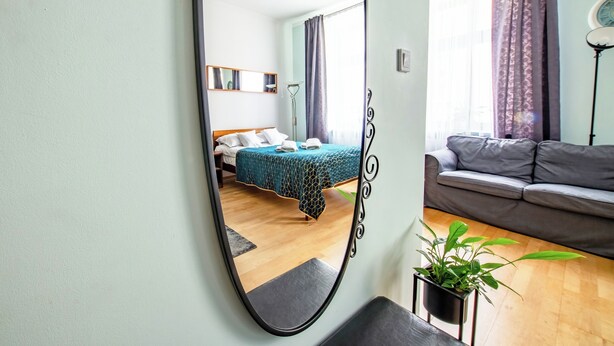 A bedroom with a bed, a sofa, a mirror, and a potted plant. - Luxury European Apartment (Kraków)