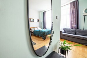Une chambre à coucher avec un lit, un canapé, un miroir et une plante en pot.