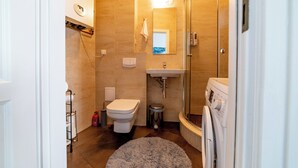 A compact bathroom with a toilet, sink, and shower. - Luxury European Apartment (Kraków)