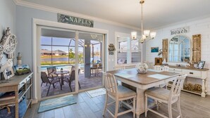 A kitchen with a large island, a dining area, and a view of a pool. - EXPERIENCE RESORT-STYLE LIVING IN THE HEART OF NAPLES RESERVE (Naples)