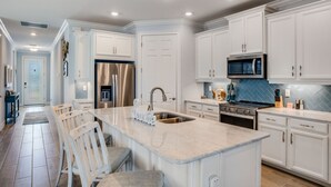 A modern kitchen with white cabinetry, stainless steel appliances, and a marble island. - EXPERIENCE RESORT-STYLE LIVING IN THE HEART OF NAPLES RESERVE (Naples)