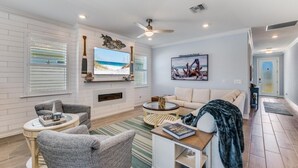 A spacious living room with a fireplace, a ceiling fan, and a large window with blinds. - EXPERIENCE RESORT-STYLE LIVING IN THE HEART OF NAPLES RESERVE (Naples)