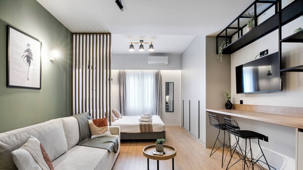 Ein modernes Wohnzimmer mit einer Couch, einem Couchtisch und einem an der Wand montierten Fernseher.