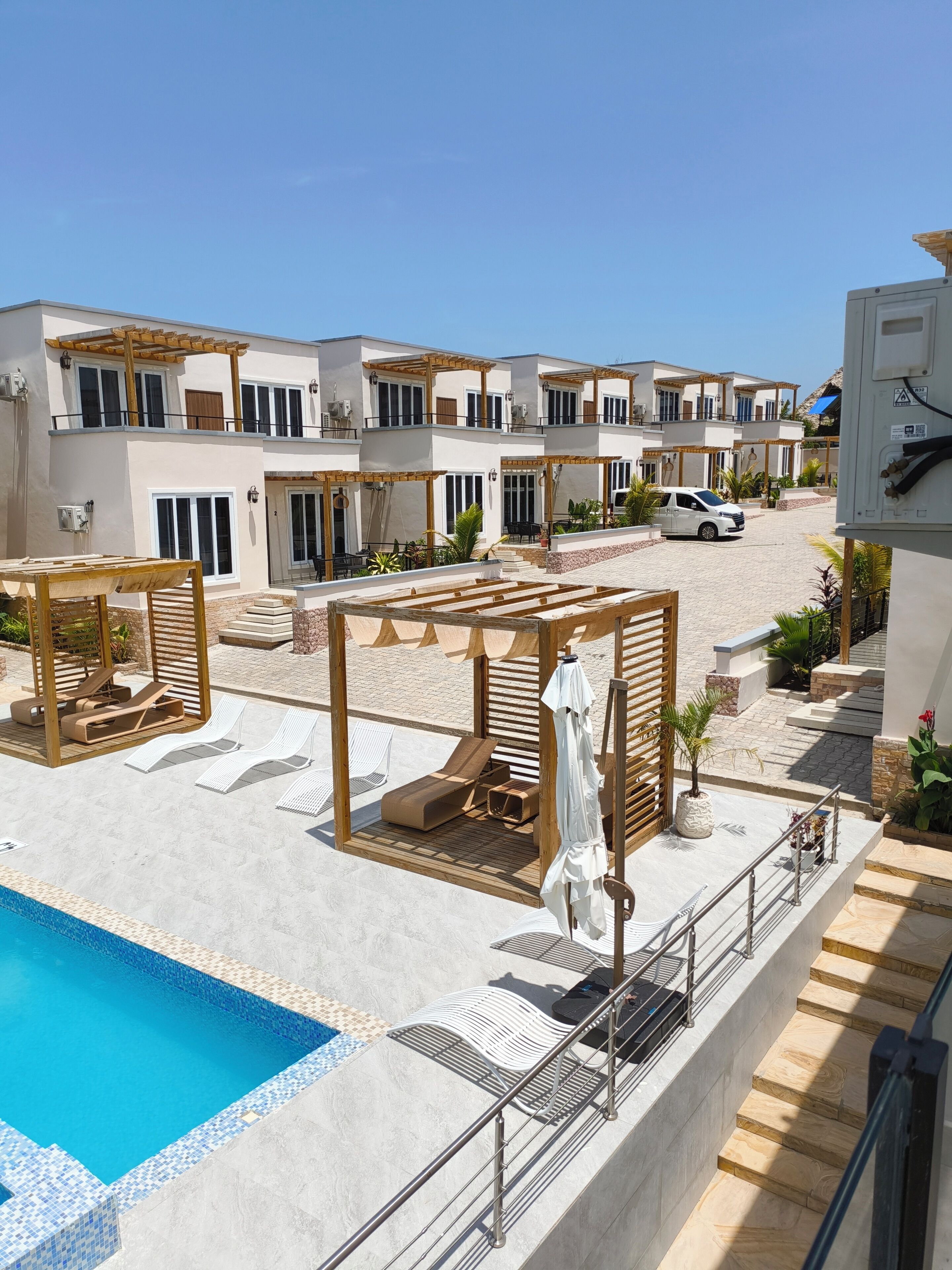 Un moderno resort con piscina, tumbonas y una zona de estar cubierta.