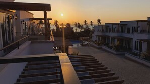 A staircase leading to a rooftop area with a sunset view, modern buildings, and palm trees. - Royal Apartment (Michamvi)
