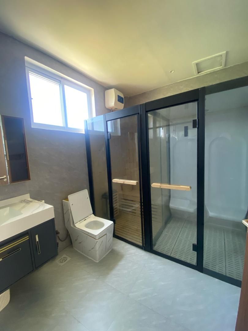 Een moderne badkamer met toilet, wastafel en douchehoek.