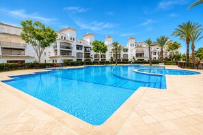 Une piscine dotée d’une terrasse carrelée, entourée d’immeubles à plusieurs étages avec des balcons.