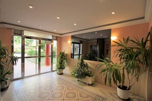 Enter a welcoming space with a patterned floor and lush greenery, surrounded by warm tones and natural light.