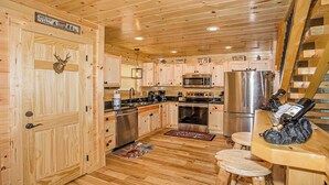 A cabin-style kitchen with wooden walls, a stainless steel refrigerator, a microwave, and a sink. - Wild Honey- 4bdrm, Incredible Mtn Views, Pool Table, Fire Pit, Pool Access (Sevierville)