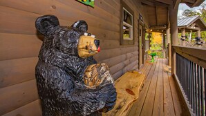 Une cabane en bois avec une sculpture d’ours sur le porche.