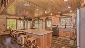 Une cuisine de style rustique, avec un îlot central, des tabourets en bois et un four encastré.