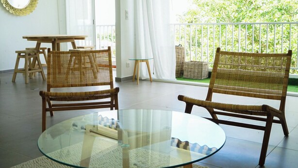 A room with two wicker chairs, a glass table, and a view of greenery outside. - Le Prince D'orion in the heart of the island for families and professionals (Fort-de-France)