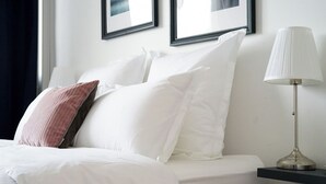 A neatly made bed with white and pink pillows, a bedside table with a lamp, and two framed pictures on the wall. - Le Prince D'orion in the heart of the island for families and professionals (Fort-de-France)