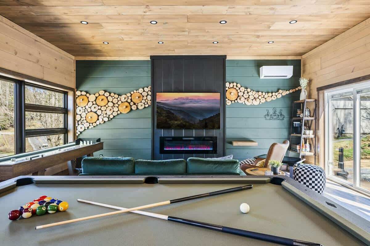 A pool table with billiard balls, a sofa, and a fireplace with a decorative wall.