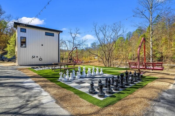 A chessboard set up on a lawn with a building in the background.