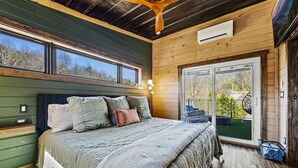Een slaapkamer met een groot bed, houten wanden en een schuifdeur naar een balkon.