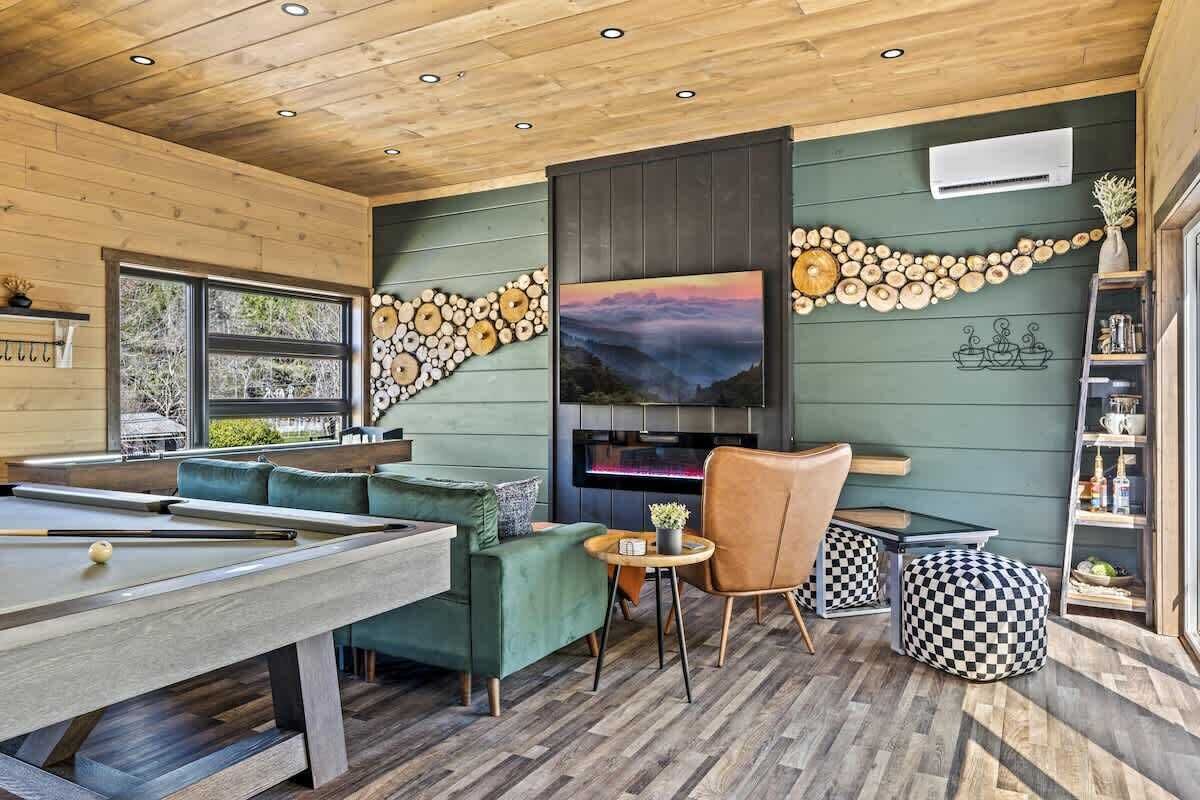 A pool table with a sofa and chairs, a fireplace, and a wall decorated with wooden circles.