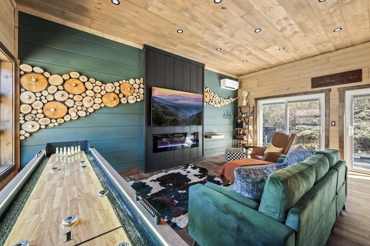 A room with a foosball table, a flat-screen TV, and a large window.
