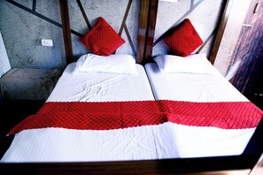 A double bed with a red and white bedspread, two red pillows, and a wooden headboard.