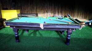 A pool table with balls, surrounded by a bamboo wall and a yellow partition. - The Escapee Resort (Dhanaulti)