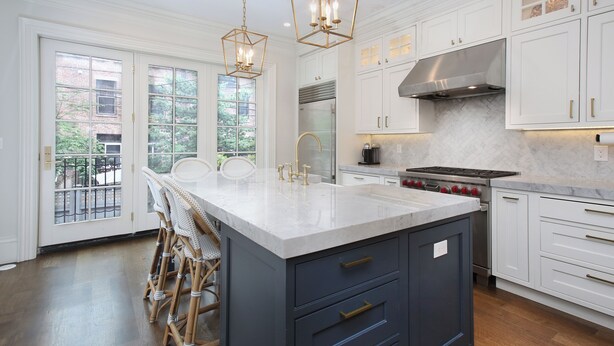 A modern kitchen with white cabinets, a large island with a sink, and a gas stove. - Renovated Boston Brownstone in Sought After Location! (Boston)