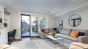A modern living room with a sofa, coffee table, and a large mirror. - Renovated Boston Brownstone in Sought After Location! (Boston)