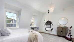 A bedroom with a large bed, a hanging chair, a guitar, and a dresser. - Renovated Boston Brownstone in Sought After Location! (Boston)