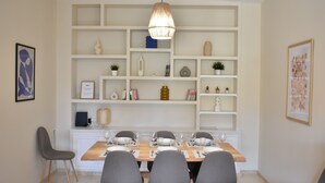 A dining area with a wooden table set for six, surrounded by grey chairs, and a hanging pendant light above. - Downtown Apartment with Parking and Terrace (Córdoba)