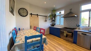 Una cocina compacta con suelo de madera, una mesa de comedor con sillas, un reloj y una ventana con vistas.