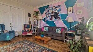 Una sala de estar con sofá, sillón, mesa de centro y una alfombra colorida.