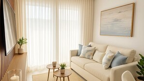 A modern living room with a beige sofa, two round coffee tables, and a wooden sideboard. - Residence del Maestro Apartments (Asunción)