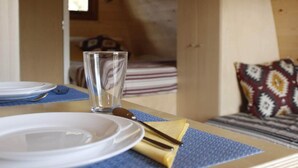 A neatly set dining table with plates, cutlery, and a glass in a cozy cabin interior.