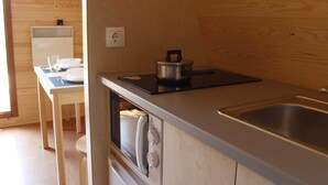 A compact kitchen with a stove, sink, and a small dining area with a table and chairs.