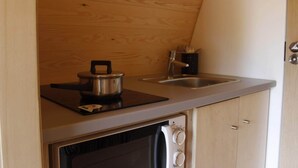 A compact kitchenette with a stove, a sink, and a small cabinet.