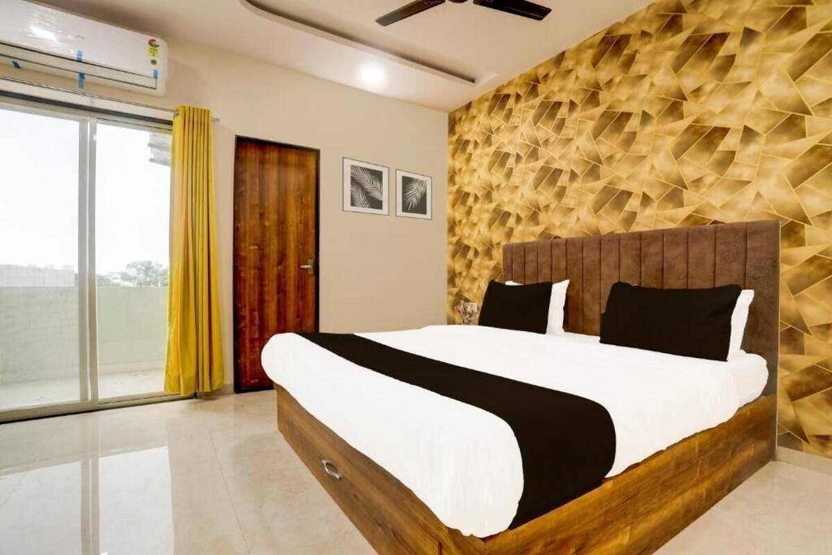 A modern bedroom with a wooden bed frame, a textured wall, and a large window with curtains.