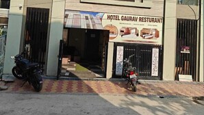 Un hôtel avec une enseigne indiquant « Restaurant Hôtel Gaurav » et une moto garée devant.
