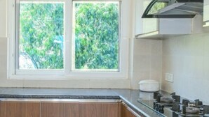 Una cocina moderna con armarios de madera, encimera negra y ventana con vistas a árboles.