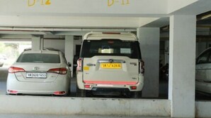 Un aparcamiento con dos coches blancos estacionados bajo una estructura marcada D-12 y D-11.