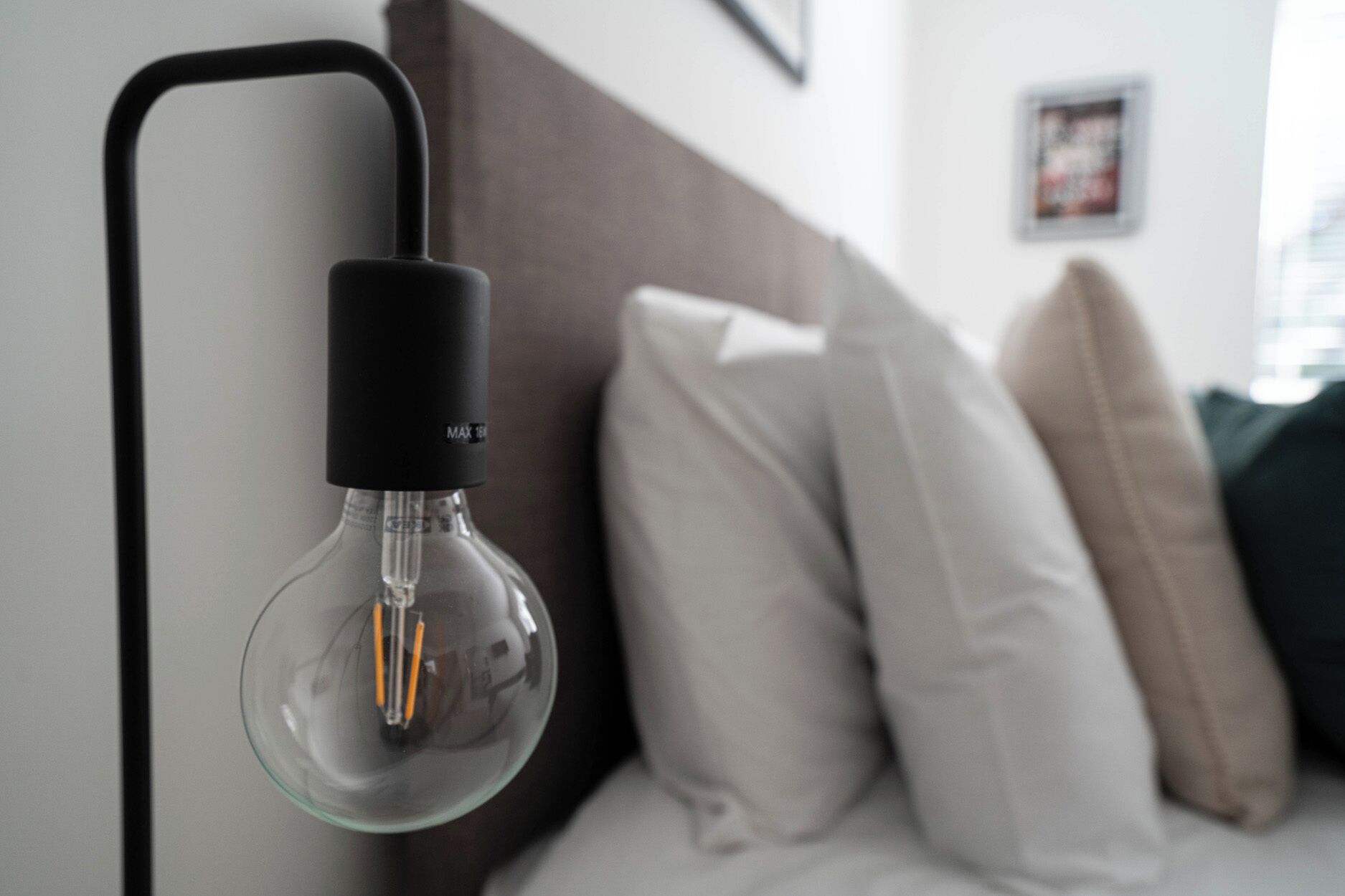 Una lámpara moderna con pantalla de vidrio transparente y base negra, fijada a la pared.