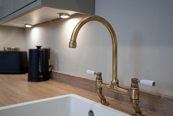 A kitchen with a modern faucet and a coffee machine on the counter. - Dunes Cottage (Lowestoft)