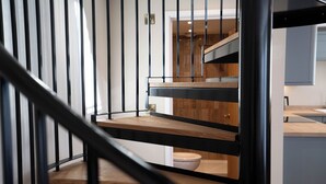 A modern staircase with black metal railings and wooden steps. - Coral Cottage (Lowestoft)